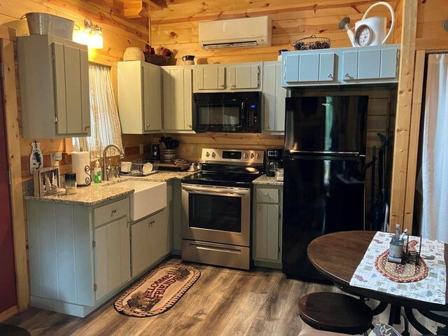 kitchen with black appliances, a wall mounted AC, dark hardwood / wood-style flooring, and wood walls