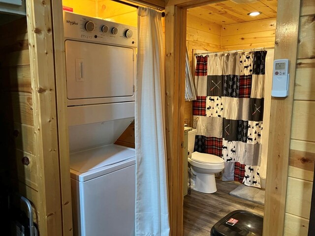 washroom with wood ceiling, hardwood / wood-style floors, and stacked washer and dryer