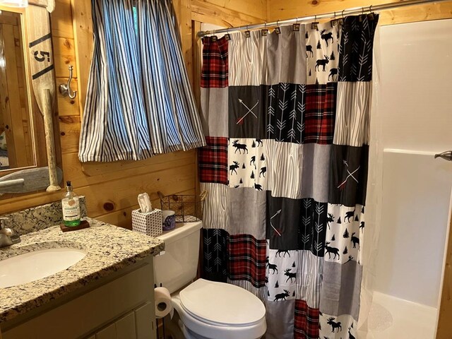 bathroom featuring vanity, toilet, curtained shower, and wooden walls