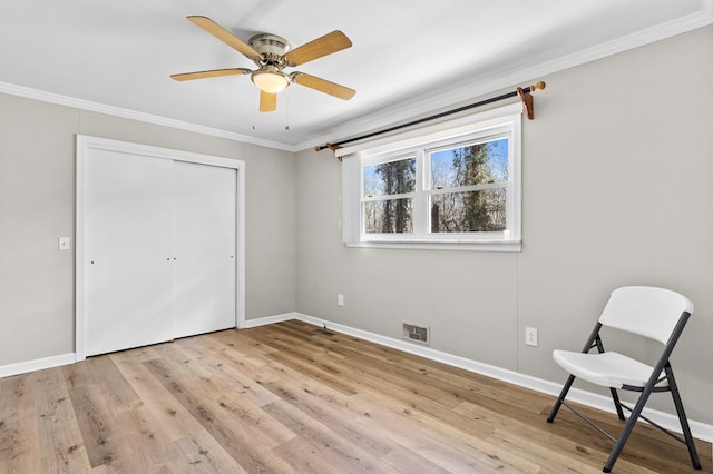 unfurnished bedroom with ceiling fan, ornamental molding, light wood-type flooring, and a closet