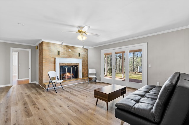 living room featuring a brick fireplace, light hardwood / wood-style flooring, ceiling fan, french doors, and ornamental molding