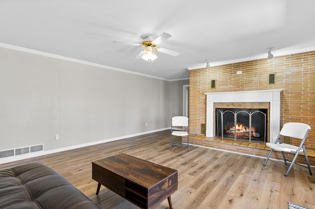 living room with a brick fireplace, ceiling fan, ornamental molding, and hardwood / wood-style floors