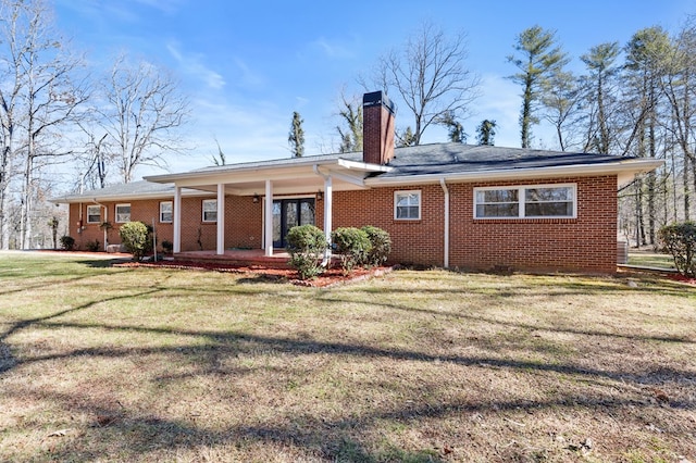 rear view of house featuring a yard and covered porch