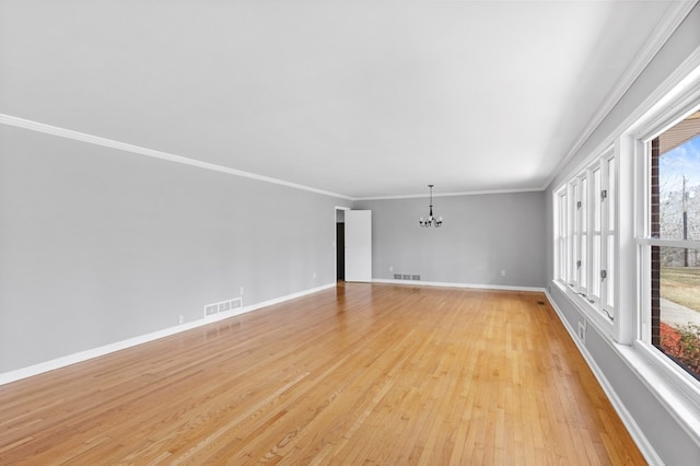 empty room featuring ornamental molding, a notable chandelier, and light hardwood / wood-style flooring