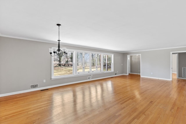 unfurnished living room featuring light hardwood / wood-style floors, crown molding, and an inviting chandelier