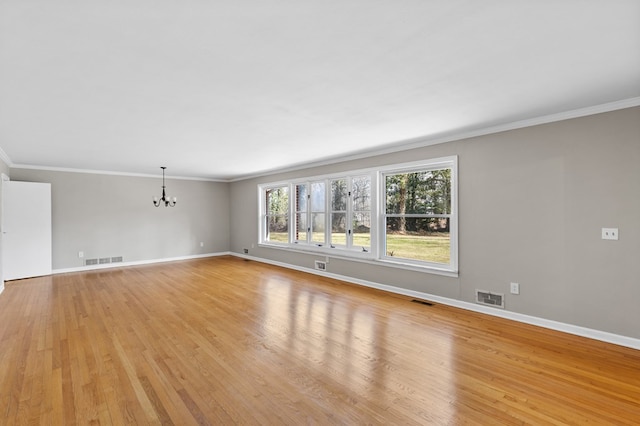 unfurnished living room with light hardwood / wood-style floors, an inviting chandelier, and crown molding