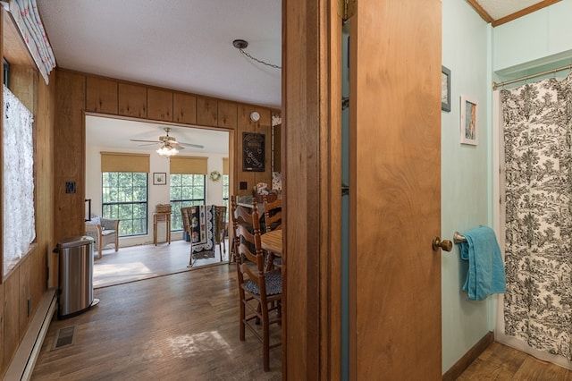 corridor featuring wood walls, dark hardwood / wood-style flooring, and a baseboard heating unit