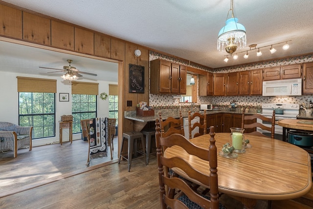 kitchen with a textured ceiling, ceiling fan with notable chandelier, white appliances, backsplash, and dark wood-type flooring