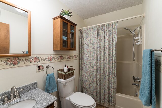 full bathroom featuring a textured ceiling, vanity, toilet, and shower / bath combination with curtain