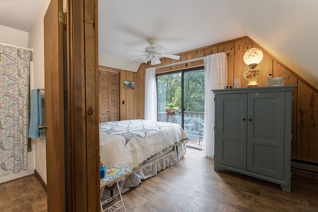 bedroom with access to exterior, ceiling fan, wooden walls, and dark wood-type flooring