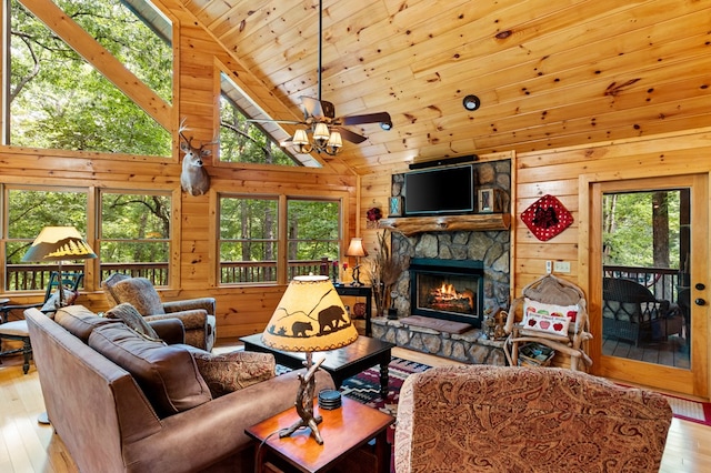 living room with wooden walls, a fireplace, ceiling fan, light hardwood / wood-style floors, and high vaulted ceiling