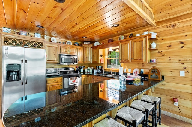 kitchen with wooden walls, light hardwood / wood-style floors, dark stone counters, wood ceiling, and appliances with stainless steel finishes