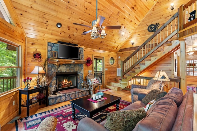 living room featuring wood walls, wood ceiling, and a stone fireplace