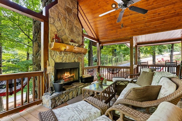 sunroom featuring an outdoor stone fireplace, ceiling fan, vaulted ceiling, and wood ceiling