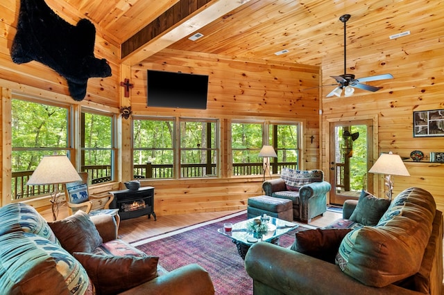 living room with wooden ceiling, a towering ceiling, ceiling fan, a wood stove, and hardwood / wood-style flooring