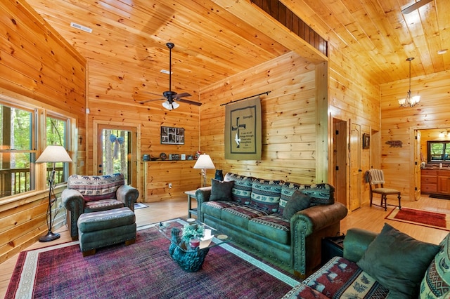 living room with ceiling fan with notable chandelier, wooden walls, wooden ceiling, and hardwood / wood-style floors