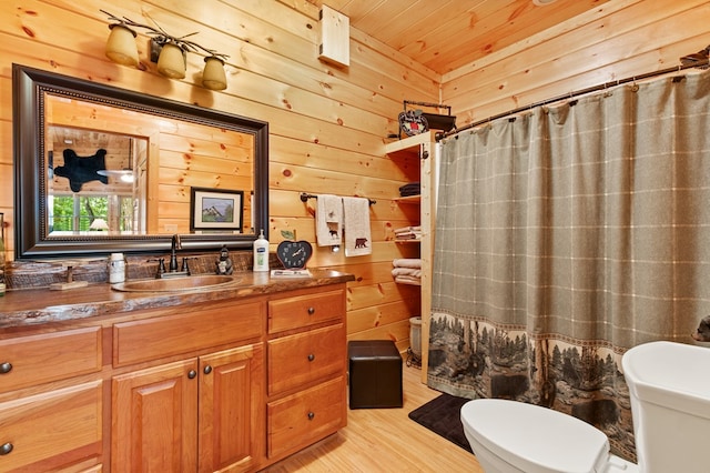 bathroom with wood walls, toilet, vanity, hardwood / wood-style flooring, and curtained shower