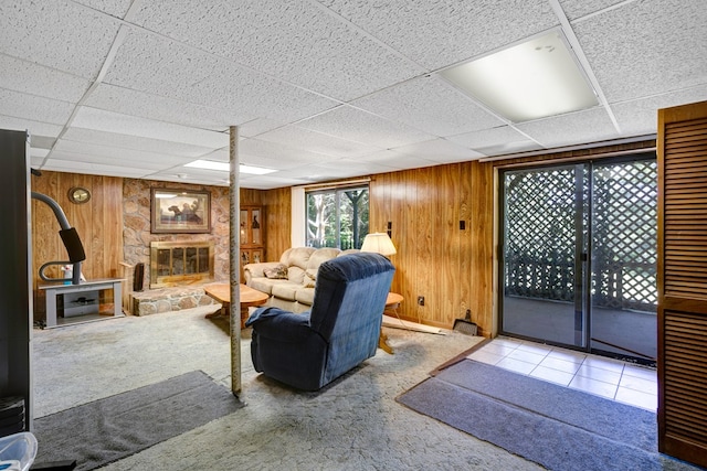 living room featuring a drop ceiling, wooden walls, and carpet flooring