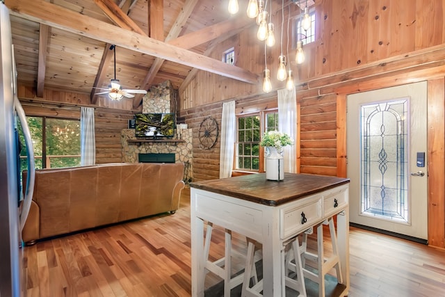 kitchen featuring beam ceiling, a fireplace, butcher block counters, light wood-style flooring, and wood ceiling