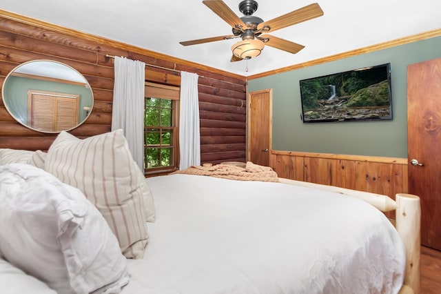 bedroom with rustic walls, ornamental molding, a ceiling fan, and wainscoting