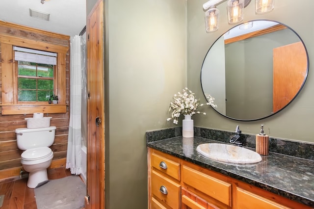 full bath with visible vents, a shower with shower curtain, toilet, vanity, and wood finished floors