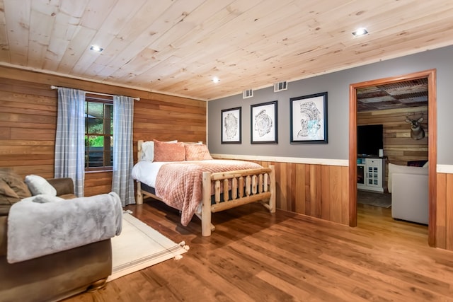 bedroom featuring wooden ceiling, wooden walls, visible vents, and light wood finished floors