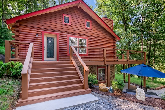 view of front facade featuring log exterior and a wooden deck