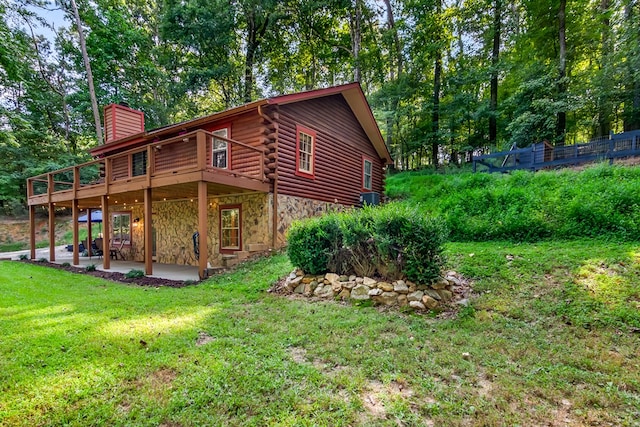 view of home's exterior featuring a patio, a yard, stone siding, log siding, and a chimney