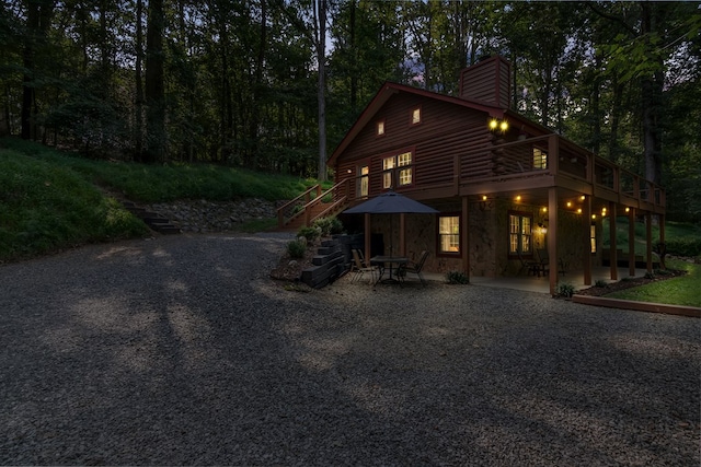 exterior space with a patio area, stairs, a chimney, and log exterior