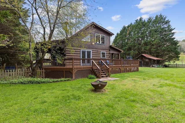rear view of property featuring a yard, a wooden deck, and fence