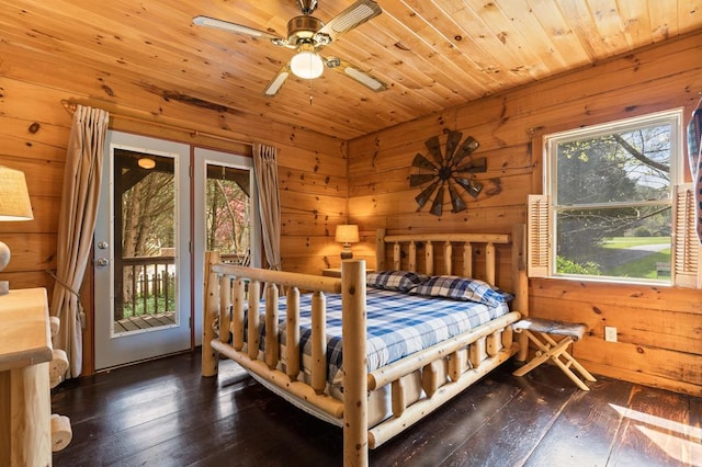 bedroom featuring wooden walls, access to outside, and hardwood / wood-style flooring