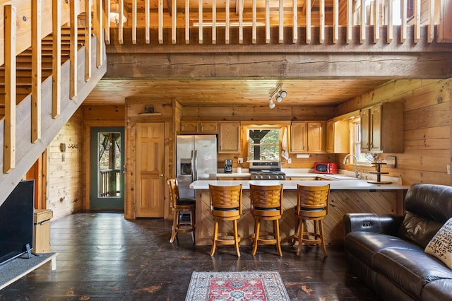 kitchen featuring a sink, light countertops, wooden walls, and stainless steel appliances