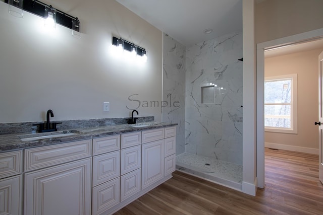 bathroom featuring hardwood / wood-style flooring, vanity, and a tile shower