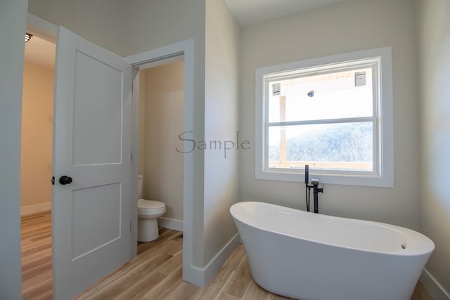 bathroom with toilet, a bath, and hardwood / wood-style flooring