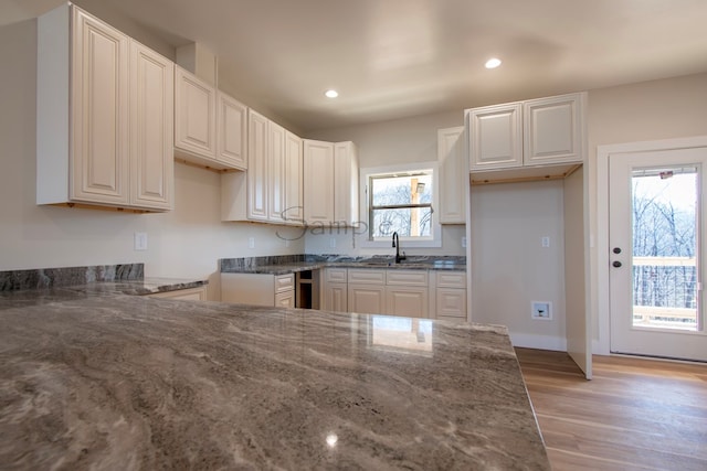 kitchen with white cabinets, a healthy amount of sunlight, dark stone counters, and light wood-type flooring