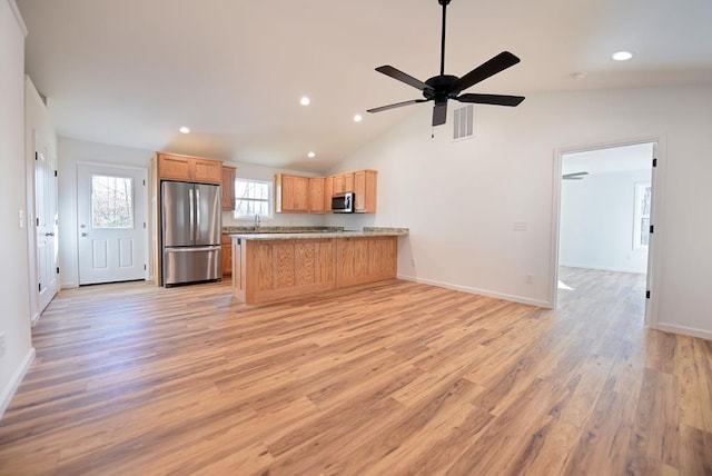 kitchen featuring kitchen peninsula, appliances with stainless steel finishes, vaulted ceiling, ceiling fan, and light hardwood / wood-style flooring