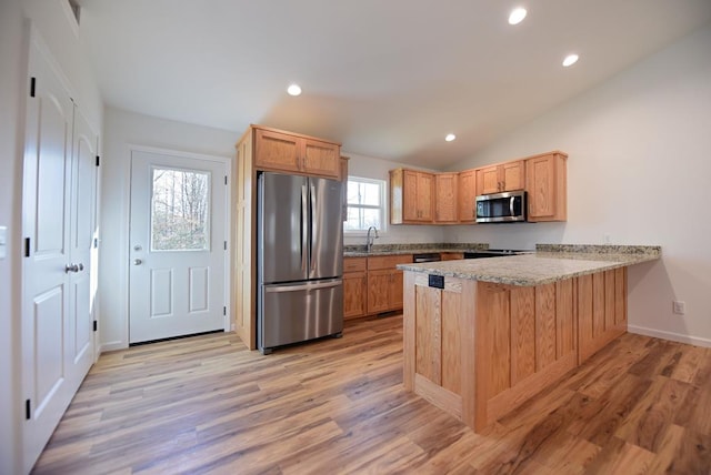 kitchen with kitchen peninsula, light hardwood / wood-style floors, lofted ceiling, a kitchen bar, and appliances with stainless steel finishes