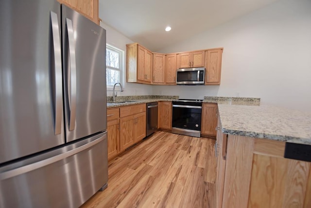 kitchen featuring lofted ceiling, sink, light hardwood / wood-style flooring, light stone countertops, and appliances with stainless steel finishes