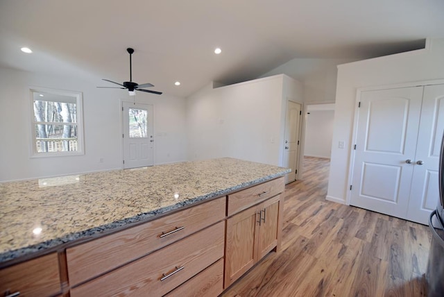 kitchen featuring light stone countertops, light wood-type flooring, ceiling fan, light brown cabinets, and lofted ceiling