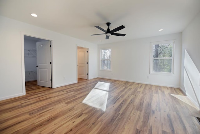 unfurnished bedroom with a walk in closet, ceiling fan, a closet, and light hardwood / wood-style floors