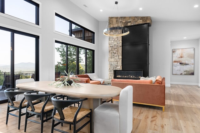 dining space featuring a mountain view, a stone fireplace, light hardwood / wood-style floors, and a healthy amount of sunlight