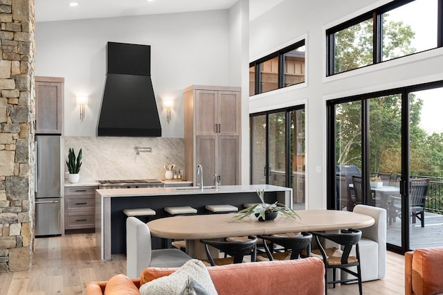 dining space featuring a high ceiling, sink, and light hardwood / wood-style floors