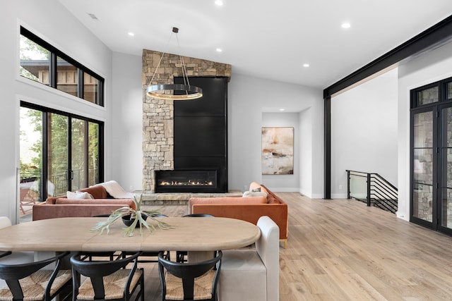 dining room featuring a fireplace, high vaulted ceiling, and light wood-type flooring