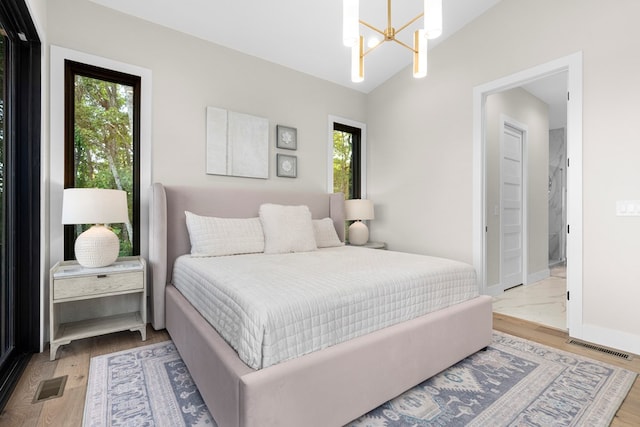 bedroom featuring vaulted ceiling, wood-type flooring, and a notable chandelier