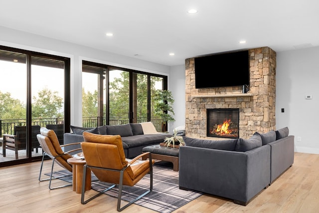 living room featuring a stone fireplace and light hardwood / wood-style floors