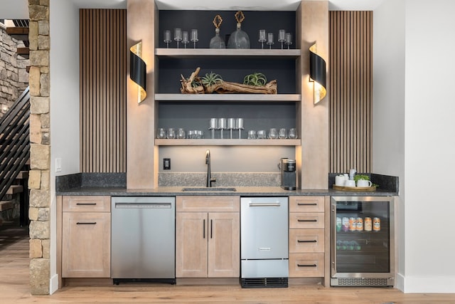 bar with sink, light brown cabinets, stainless steel dishwasher, beverage cooler, and light hardwood / wood-style floors