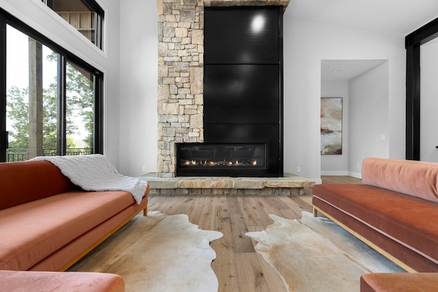 living room featuring hardwood / wood-style floors, a towering ceiling, and a large fireplace