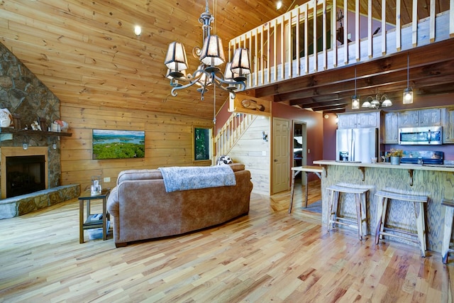 living room featuring light hardwood / wood-style floors, a towering ceiling, an inviting chandelier, and a fireplace