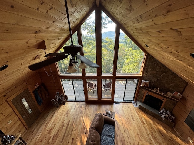 living room with lofted ceiling, a fireplace, wooden walls, hardwood / wood-style floors, and ceiling fan