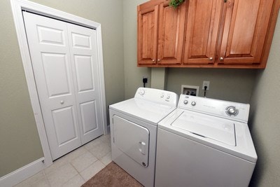 laundry area with cabinets, light tile patterned floors, and washing machine and dryer